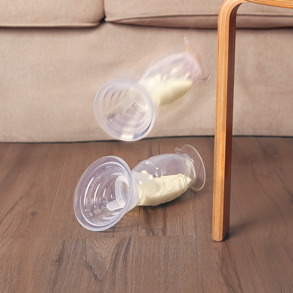 Breast pump with milk spilling on wooden floor near sofa